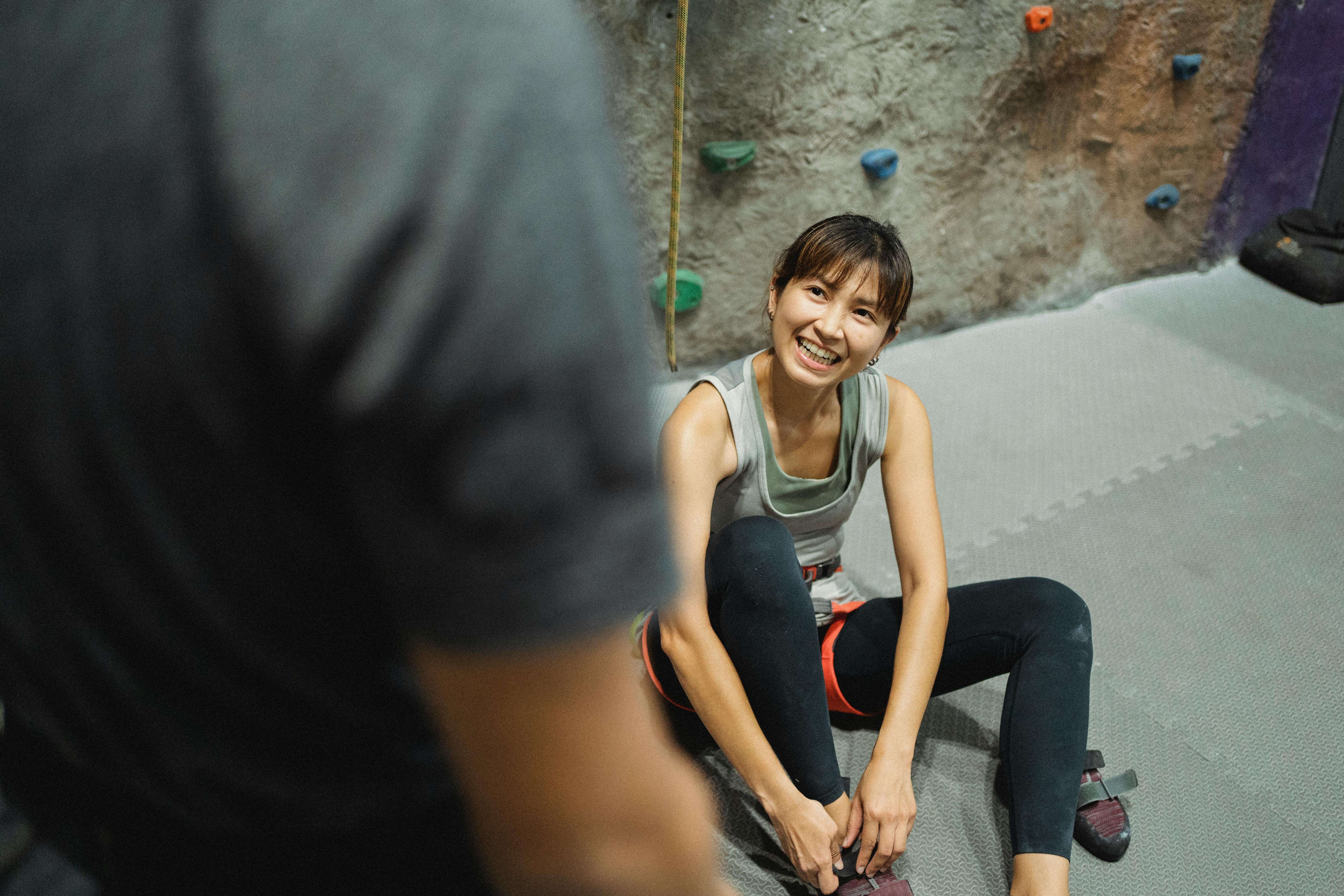 Smiling rock climber reaching for a hold at an indoor climbing gym